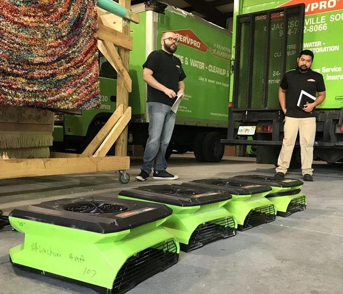Two SERVPRO trucks in a garage with two men looking at equipment. 