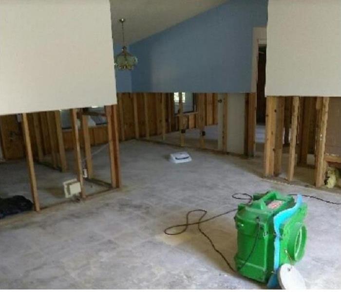 SERVPRO drying equipment in water damaged room; flood cuts on walls to enable drying